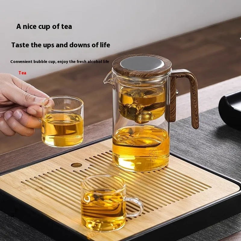 Glass teapot with wooden handle showing magnetic separation mechanism for loose leaf tea brewing