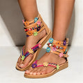 Ethnic style beaded petal sandals with floral decoration and round toe on a white background.