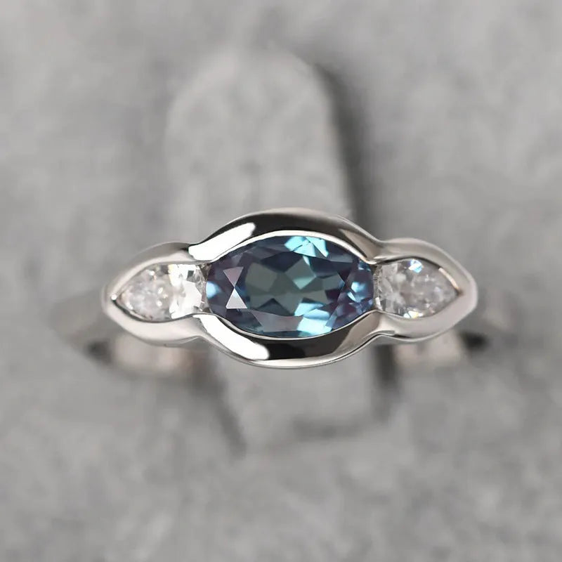 Geometric ellipse-shaped ring in white gold colour with zircon inlay, shown on a hand.