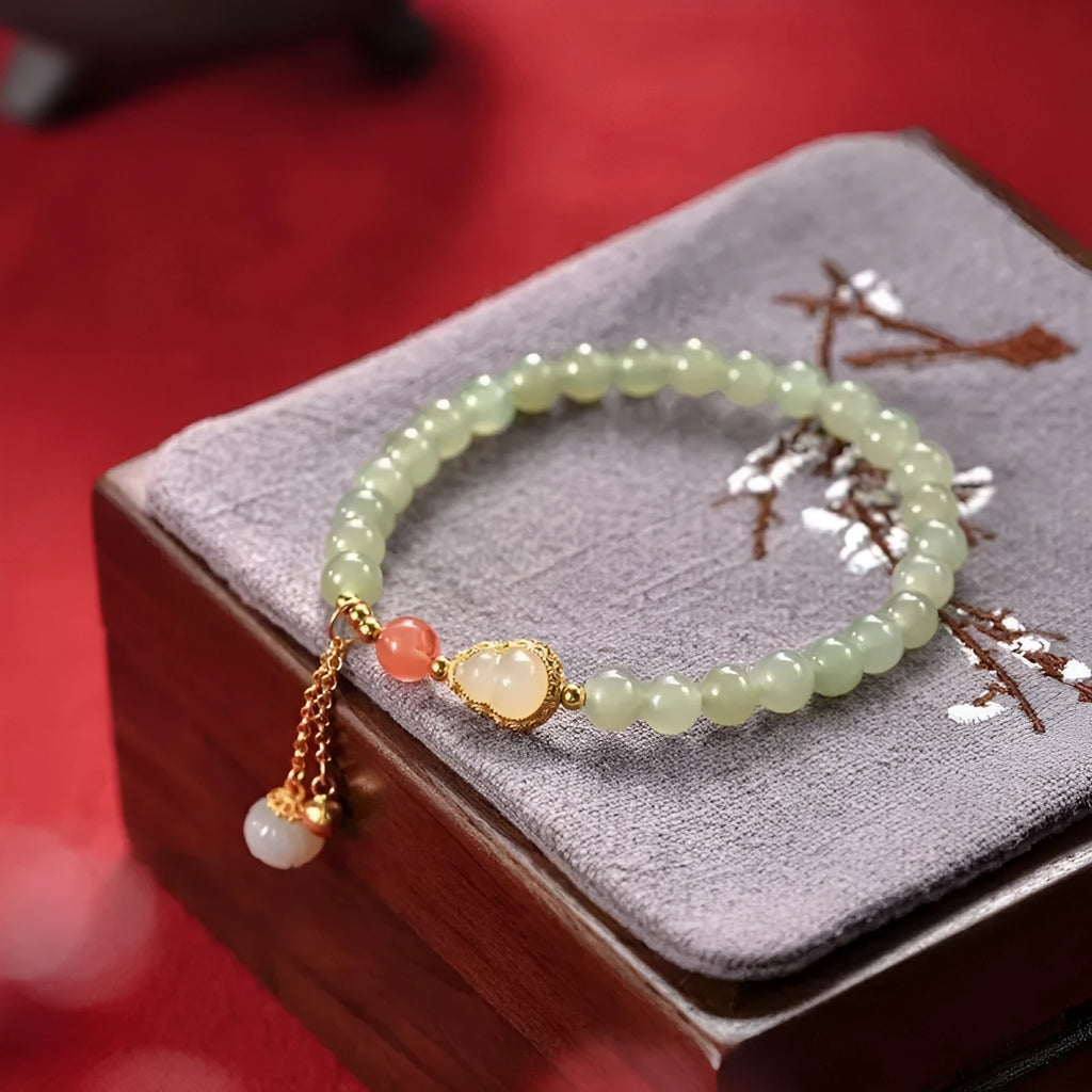 Hand-strung jade bracelet with a gold gourd charm and fu character charm.