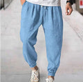 Men's loose fit cotton trousers with elasticated ankle bands in light green, shown in a casual summer setting.