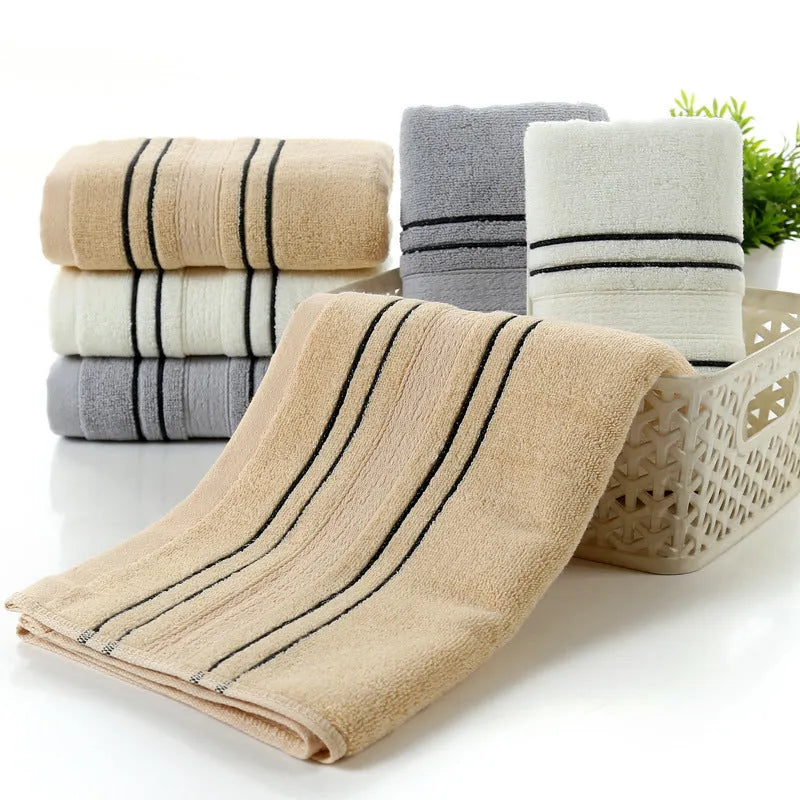 Cotton towel set showing white, grey and khaki bath towels with 34x74cm and 70x140cm dimensions