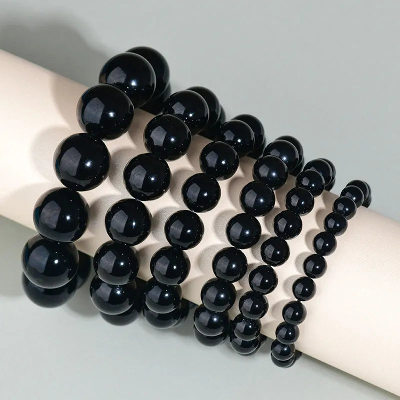 Hand-woven obsidian couple bracelets in various colours including black, silver, and rainbow eye obsidian