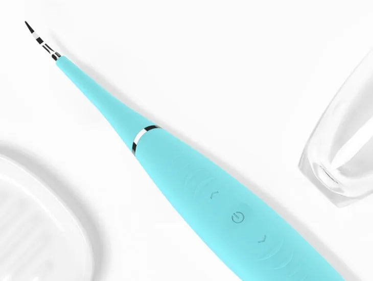 Pink and blue waterproof electric tooth scaler with integrated handle on a bathroom counter.