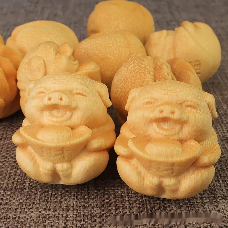 Small cute Fulu Pig bamboo carving ornament on a surface, showing its ingot shape.