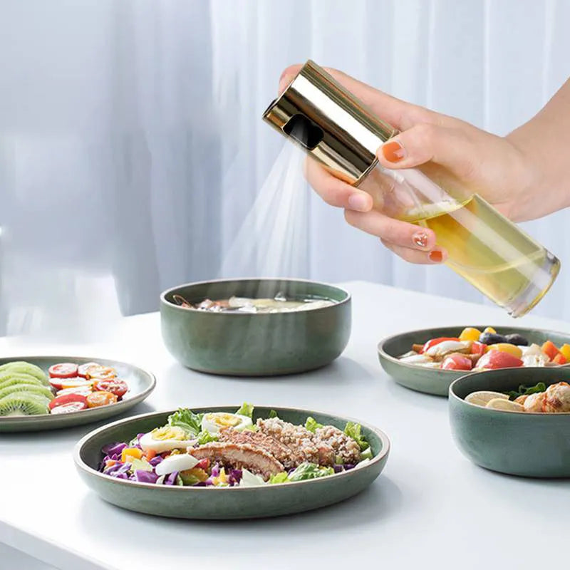 Gold push-type oil and vinegar spray bottle made of ABS plastic and glass with pump top.