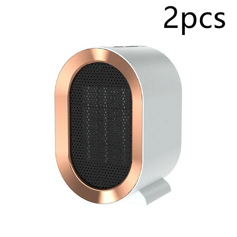 Black desktop electric fan heater with mechanical controls and UK plug on a wooden desk.