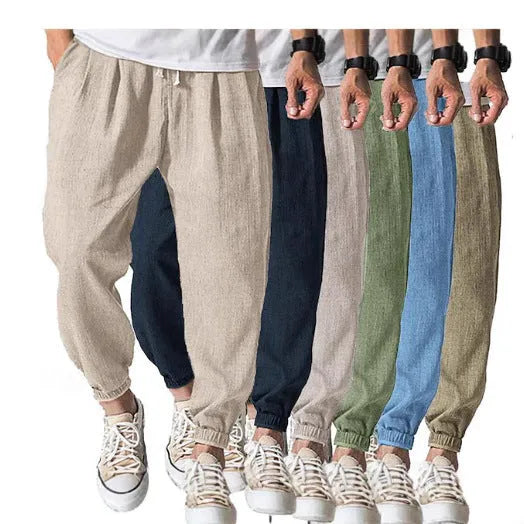 Men's loose fit cotton trousers with elasticated ankle bands in light green, shown in a casual summer setting.