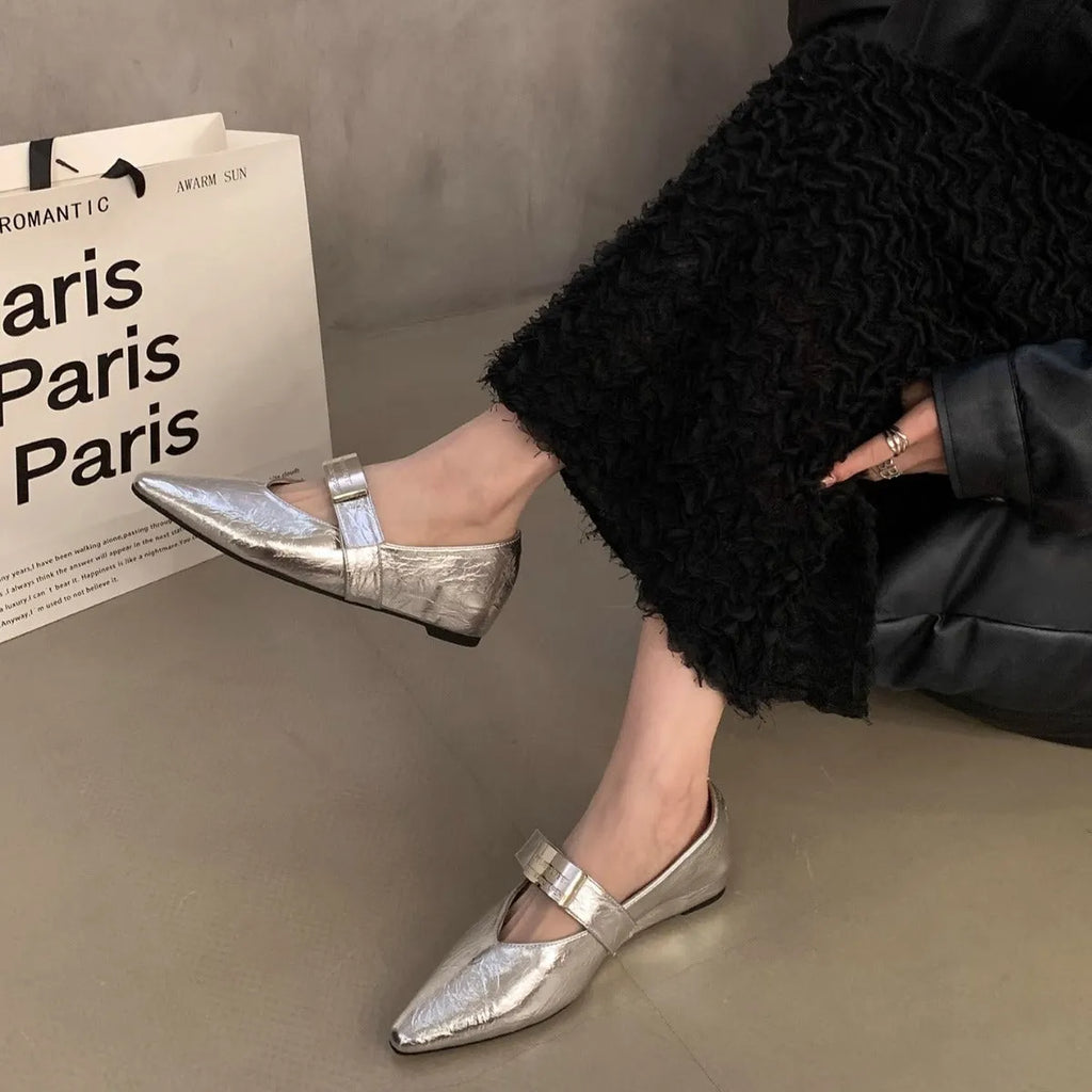 Women's black pointed toe Mary Jane shoes with a silver buckle on a low flat heel.