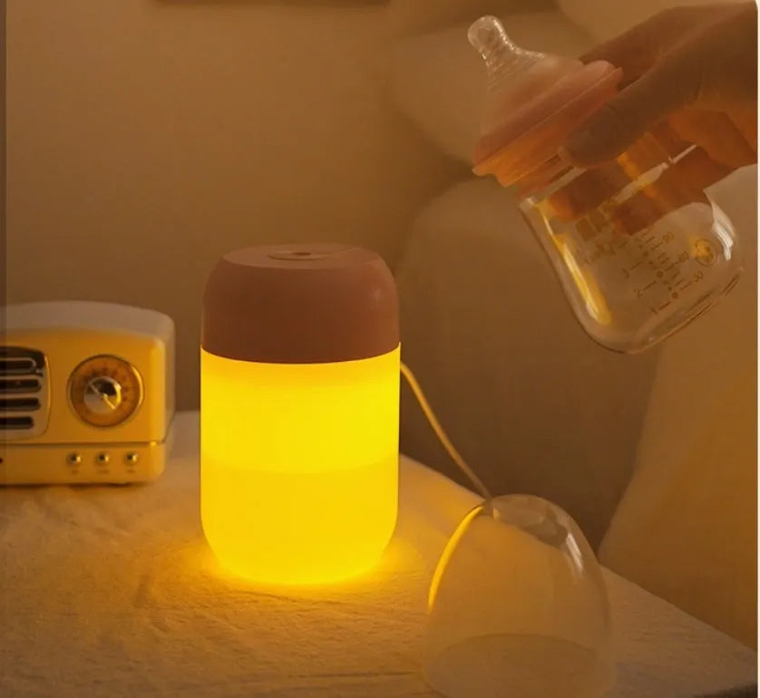 Small white cylindrical USB-powered humidifier with charging cable on a desk.