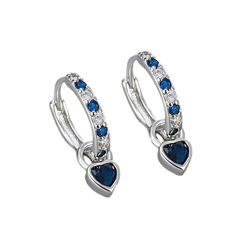 Close-up of women's fashion clip-on earrings with a heart-shaped pink cubic zirconia stone in a gold-coloured copper setting.