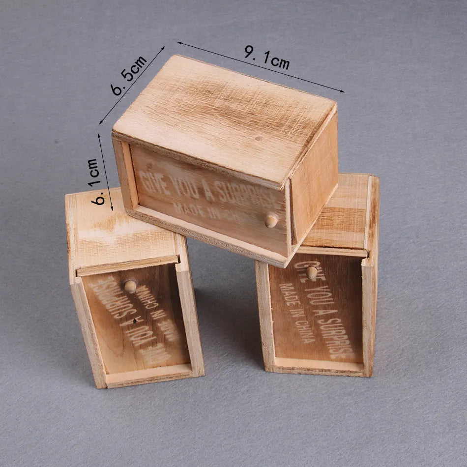 Wooden prank scare box with lid open showing a lifelike spider figurine on a spring.