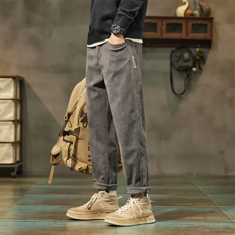 Man wearing tapered straight-leg corduroy trousers in army green, showing mid-rise waist and street style.