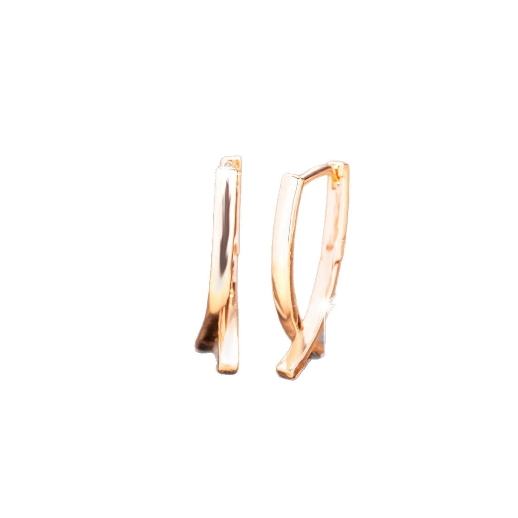 A pair of rose gold coloured cross shaped earrings made from polished copper.