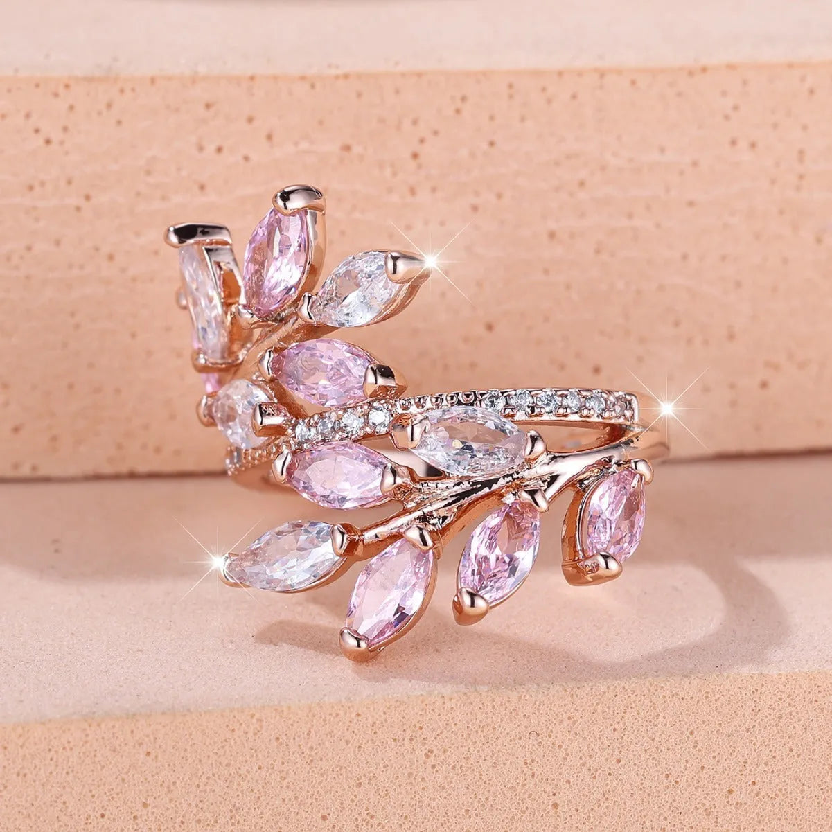 Adjustable copper leaf-shaped ring with zircon stones in various colour options on a white background.