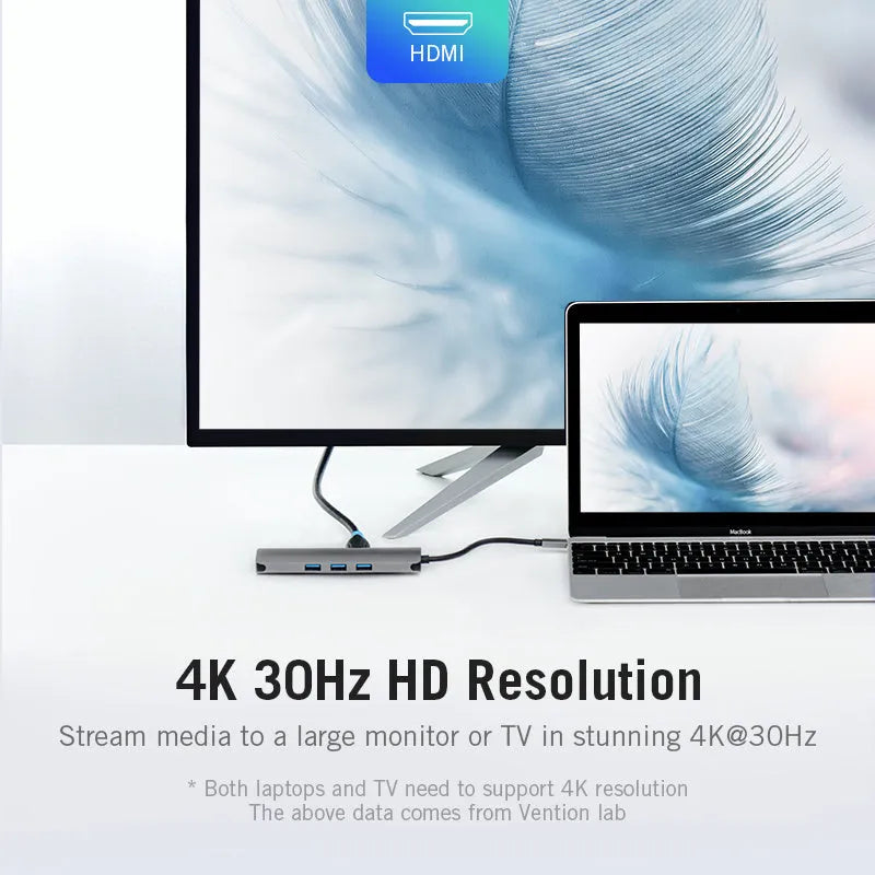 Deep grey USB-C to HDMI hub with Ethernet, USB ports, and memory card slots on a desk next to a laptop.