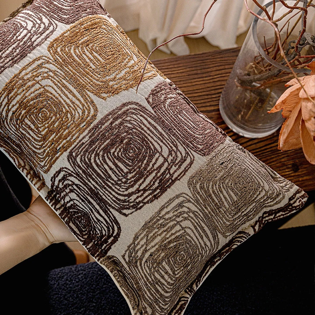 Cream and coffee-coloured abstract coil pattern square pillow cover 50x50cm on a grey sofa.