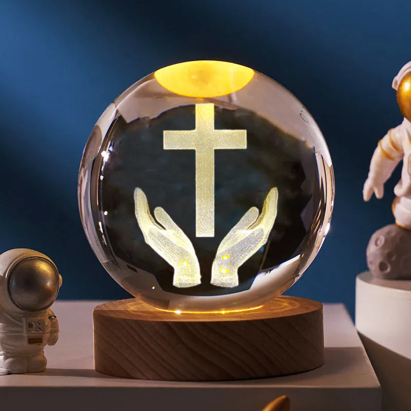 White crystal ball desk ornament on a solid wood base with a warm light, showing religious motif options.