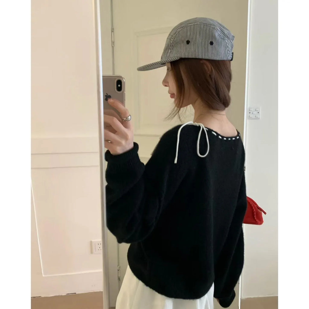 Women's loose-fitting black and grey knitwear pullover sweater on a hanger