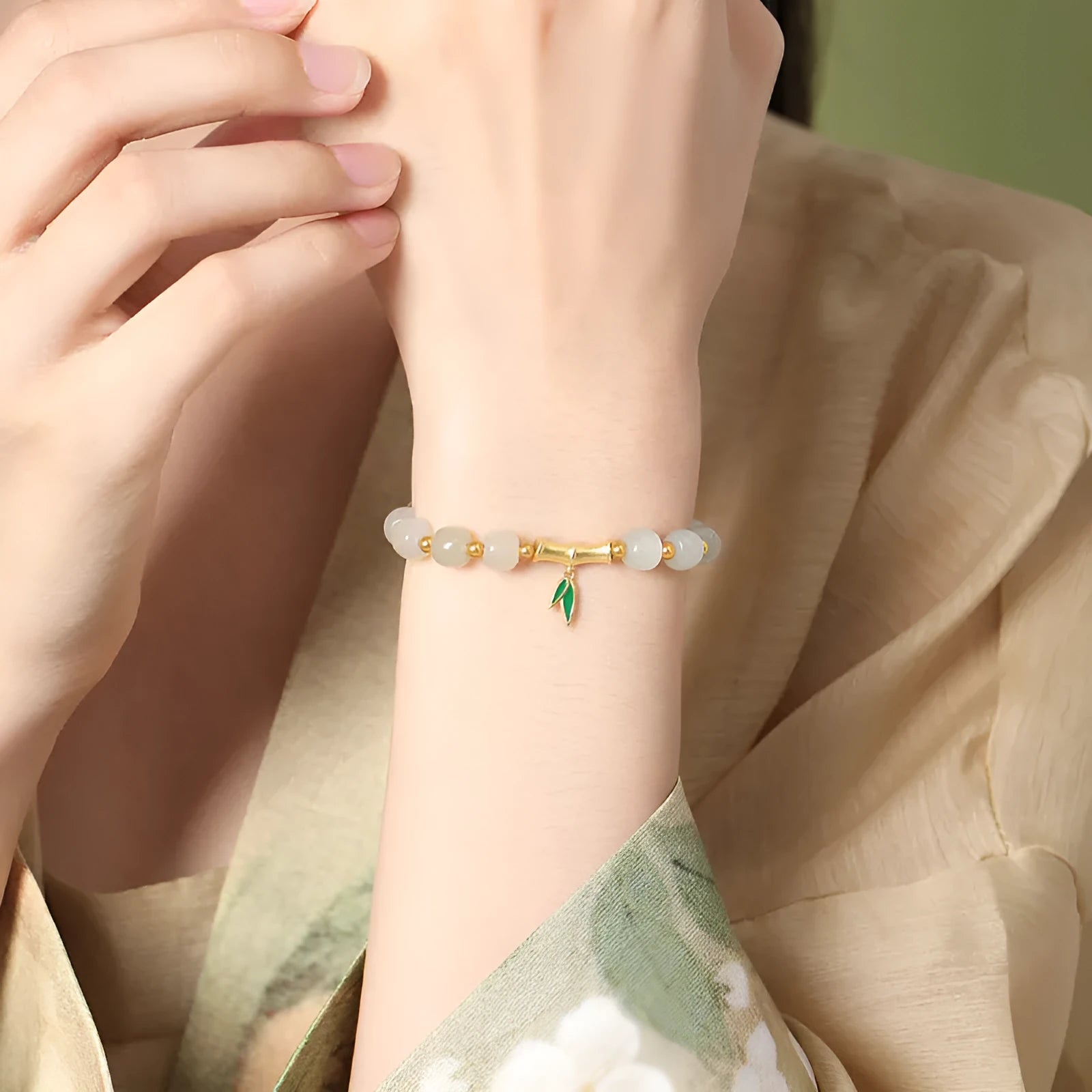 Natural Hetian jade and sterling silver bamboo leaf bracelet on a wrist, showing gold and silver finish options.