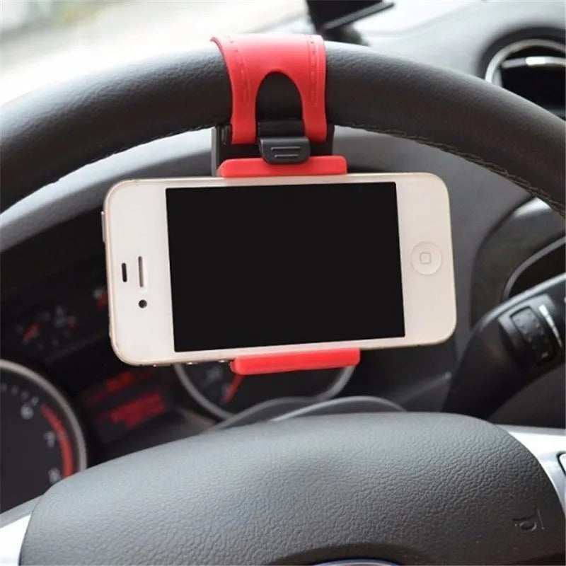 Black universal steering wheel phone holder clip mounted on a car steering wheel holding a smartphone.