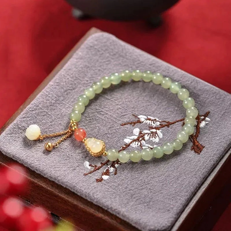Hand-strung jade bracelet with a gold gourd charm and fu character charm.