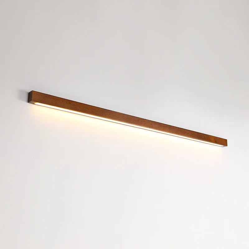 Slim walnut-coloured wood and acrylic LED strip wall lamp mounted on a wall in a modern room.