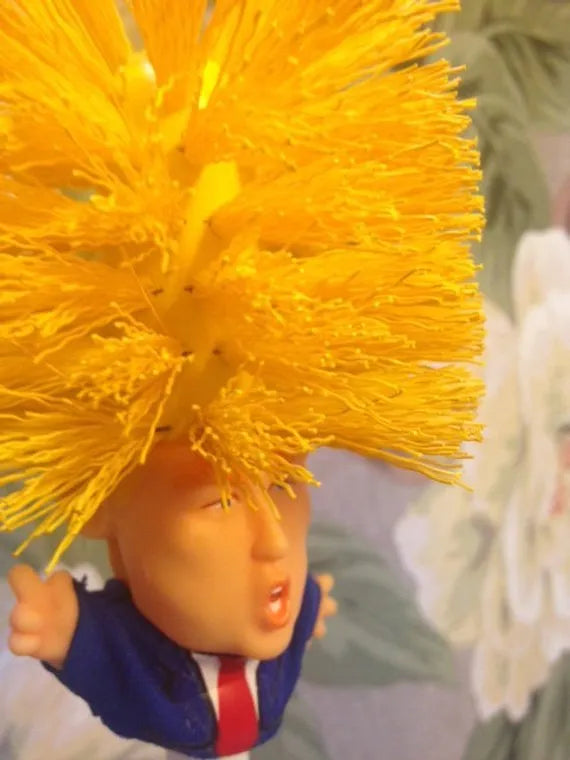 Yellow plastic Donald Trump novelty toilet brush with hanging slot.