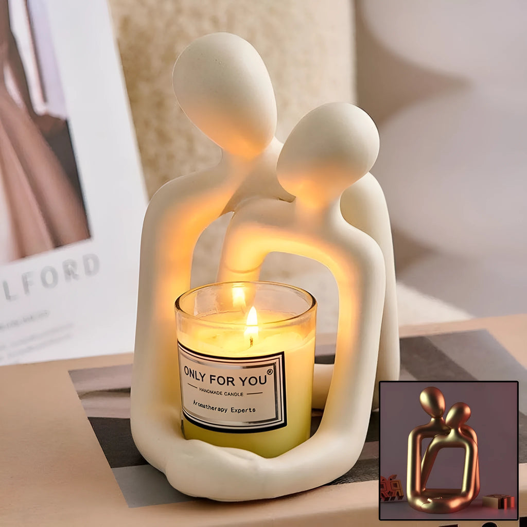 Modern resin sculpture of an embracing couple in milky white or gold finish on a wooden surface.