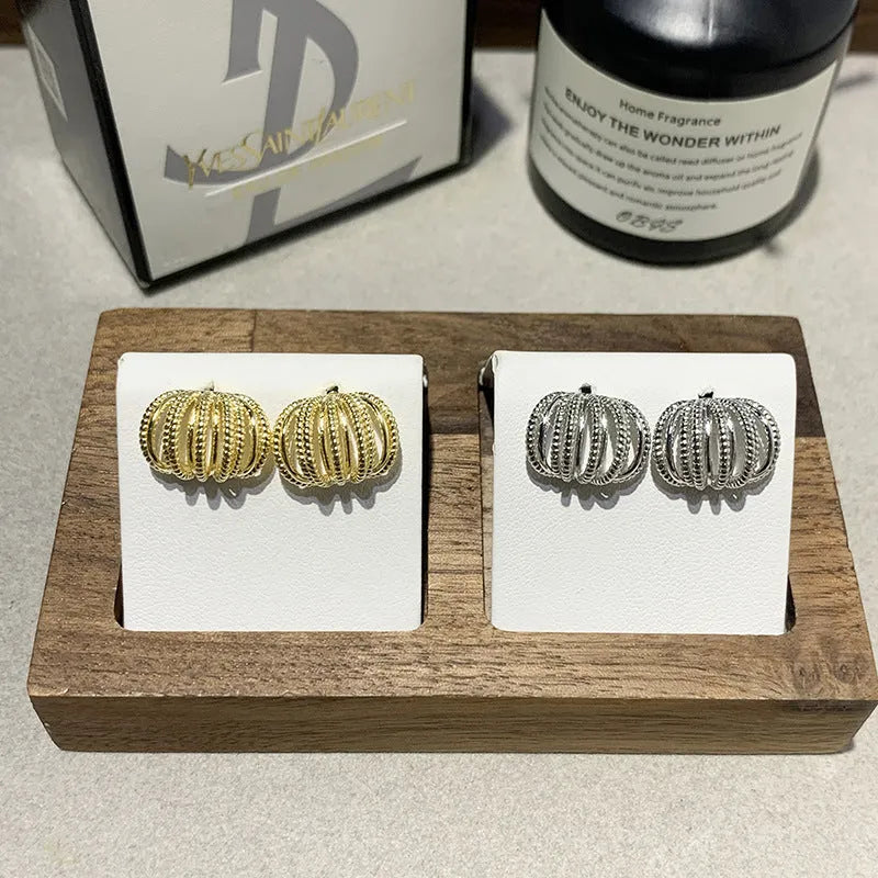 Multi layer metal wire C-ring earrings in gold and silvery colours on a neutral background