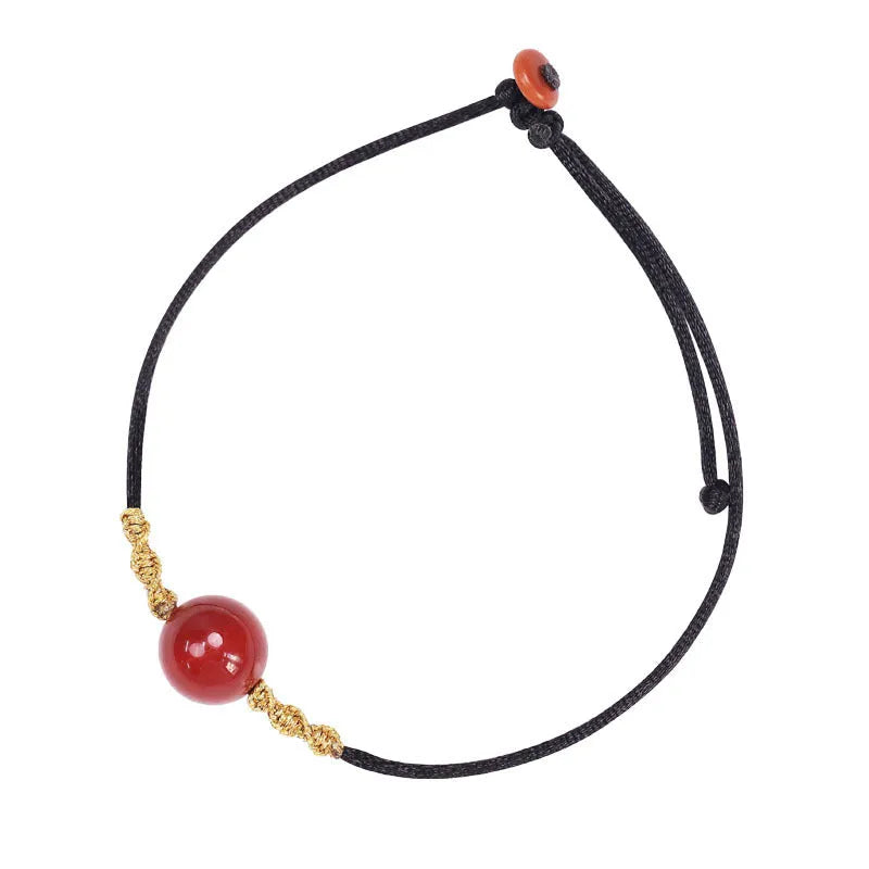 Hand-woven red agate bracelet and necklace set with bean-shaped beads on a textile background.