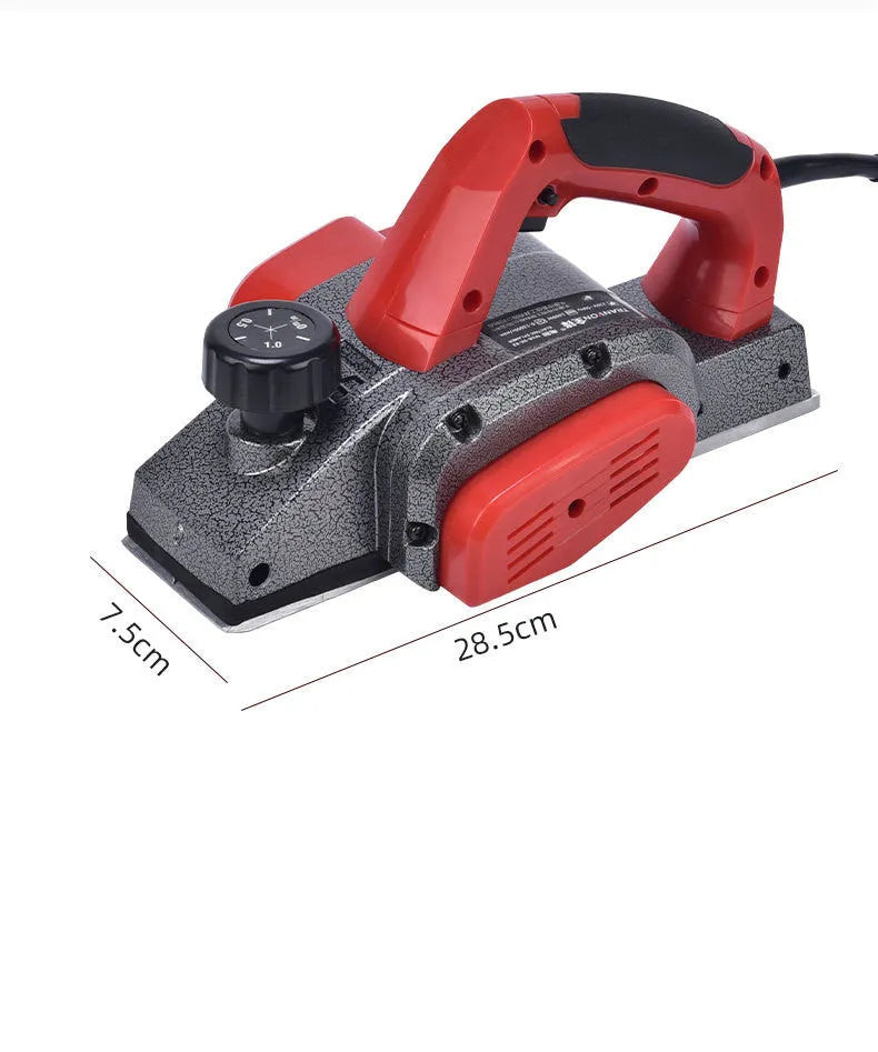 Red desktop electric wood planer with aluminium body on a workbench.