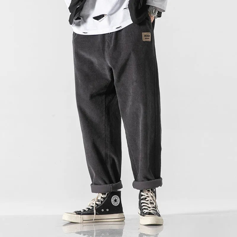 Men's loose straight-leg corduroy sports trousers in army green, laid flat to show fit and texture.