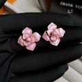 A pair of gold-plated purple floral stud earrings with silver needle details on a white background.