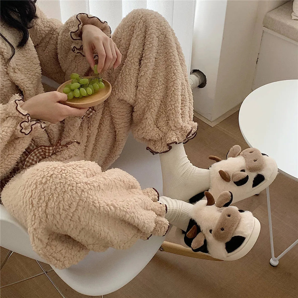 White cow print faux fur slippers for women with a non-slip textured sole.