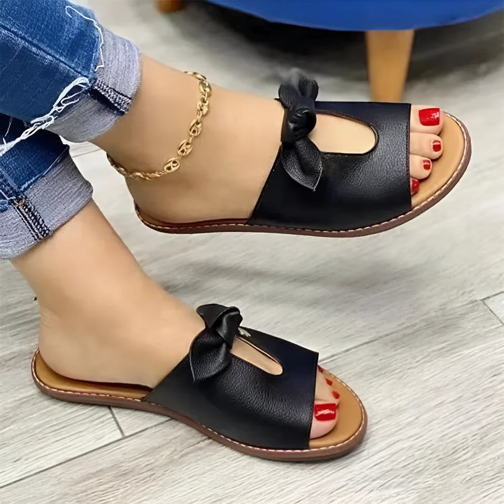 Ladies black sandals with fish mouth toe and a gold bow on the strap.