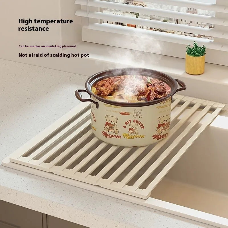 Foldable milky white stainless steel kitchen draining rack shown next to a sink.