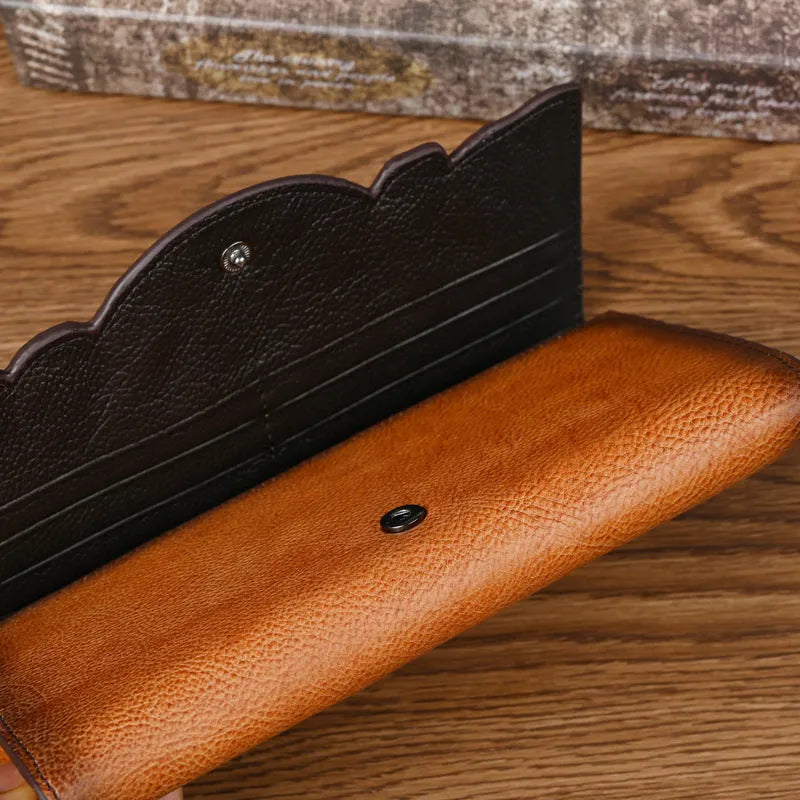 Women's brown cowhide tri-fold wallet with embossed floral pattern showing open compartments