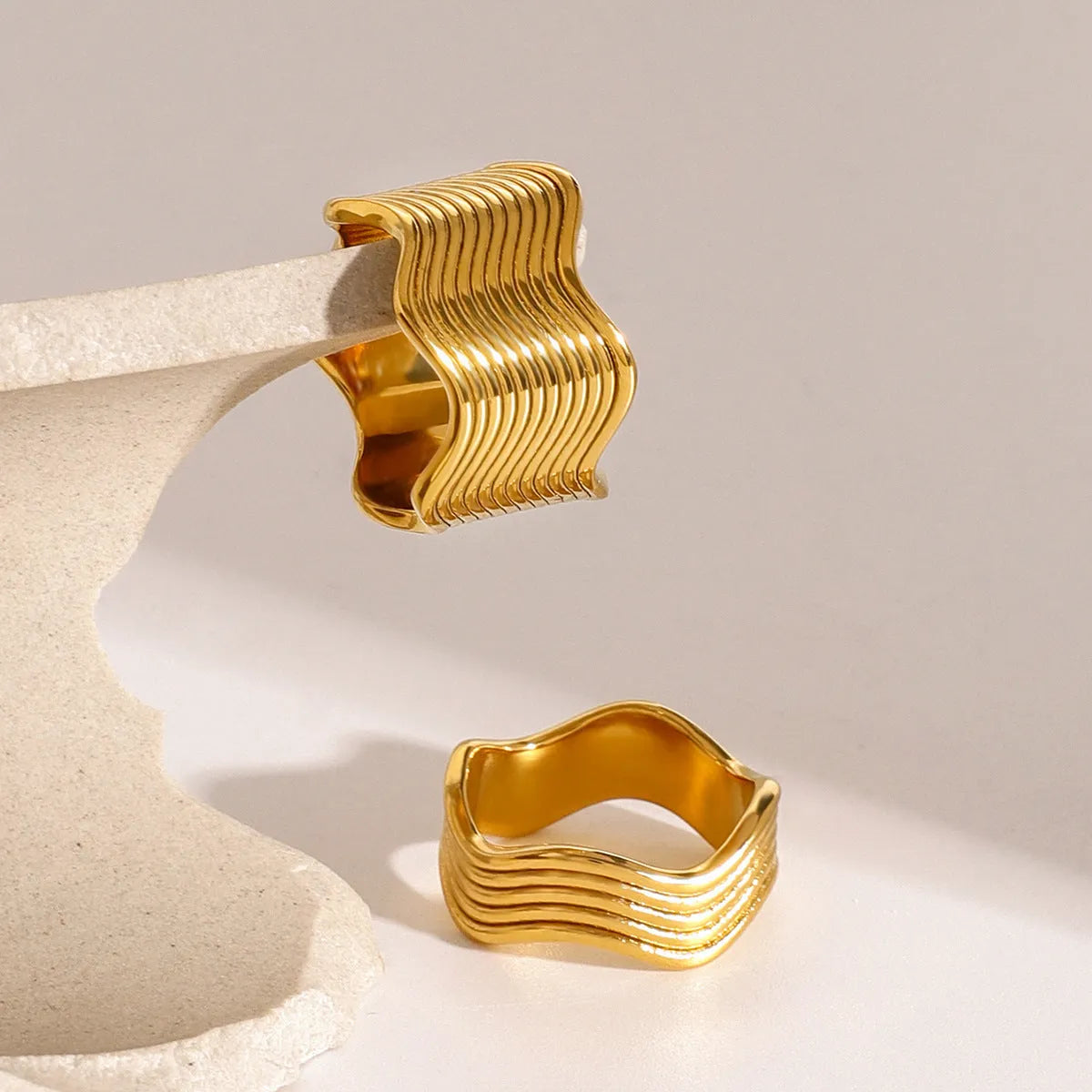 Stainless steel geometric wave ring with wide band design in silver and gold colour options.
