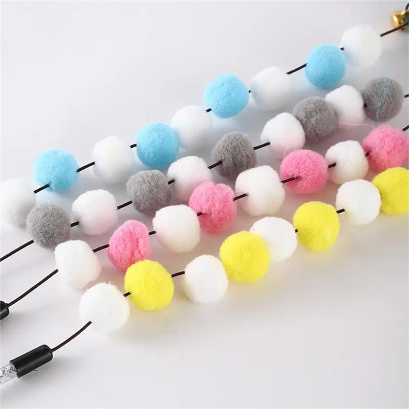 Grey, yellow, and blue acrylic pompon cat teaser stick with feather and bell, shown at 31cm length.