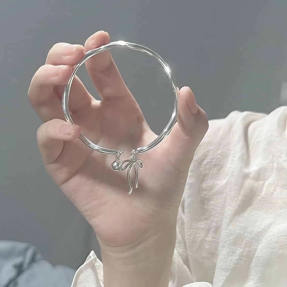 Silver adjustable bracelet with a bow charm and bell opening clasp
