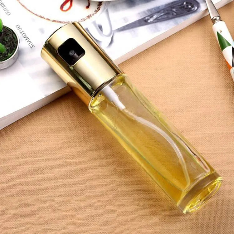 Gold push-type oil and vinegar spray bottle made of ABS plastic and glass with pump top.