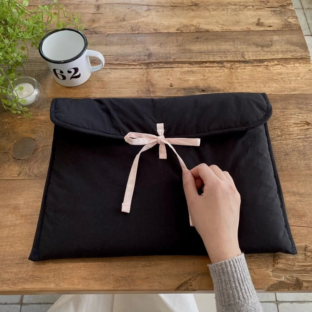 Women's black and white quilted ballet style laptop bag with bow, shown in two sizes.