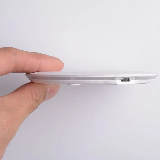 Ultra-thin wireless charger for mobile phone, black, with USB cable, showing charging indicator light