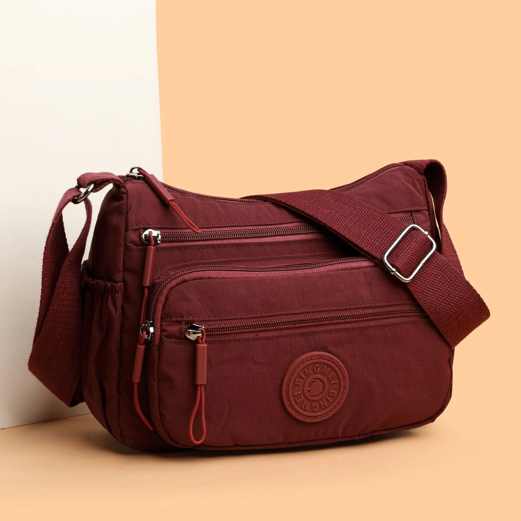 Water-repellent nylon crossbody bag with three-dimensional pockets in grey, black or red options