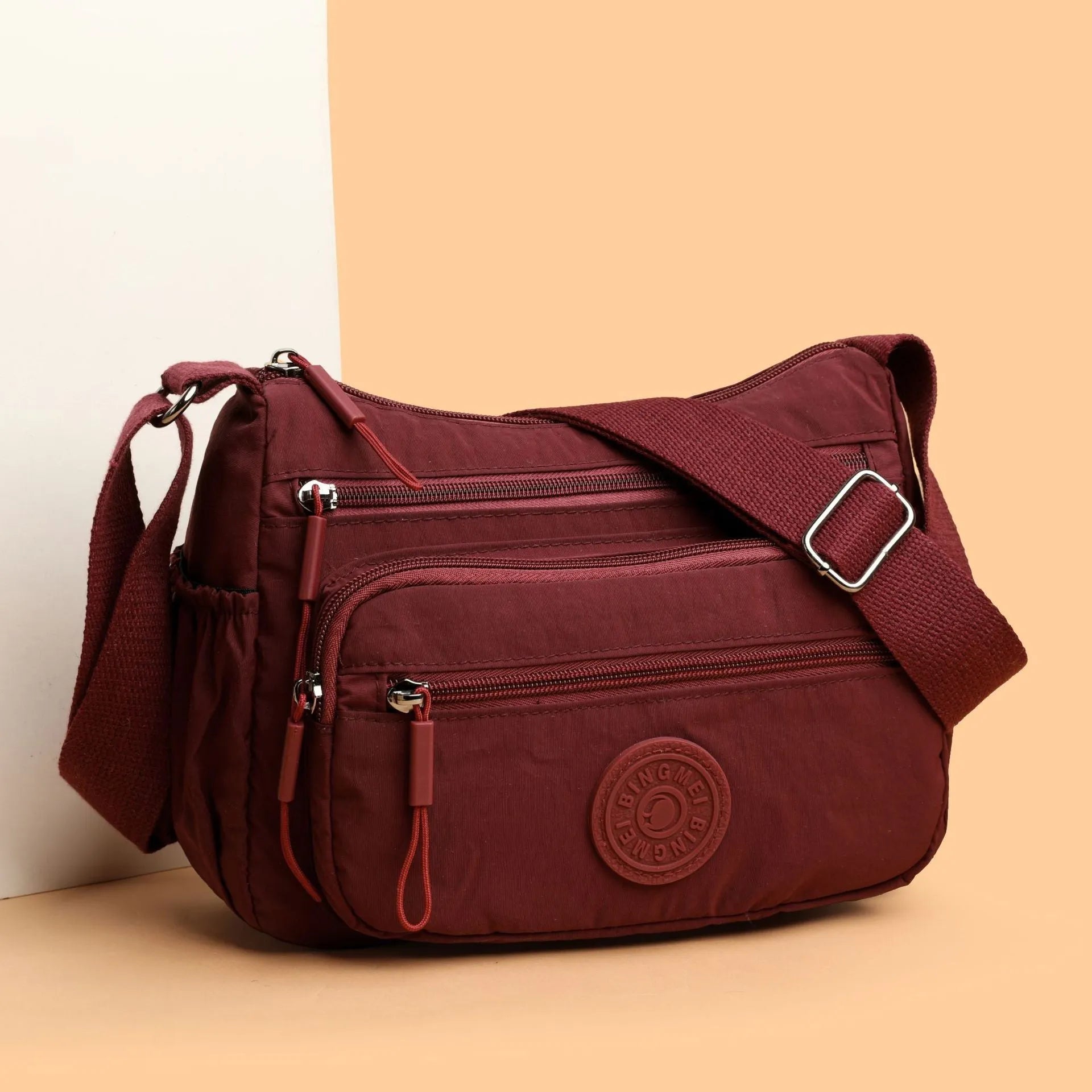 Water-repellent nylon crossbody bag with three-dimensional pockets in grey, black or red options