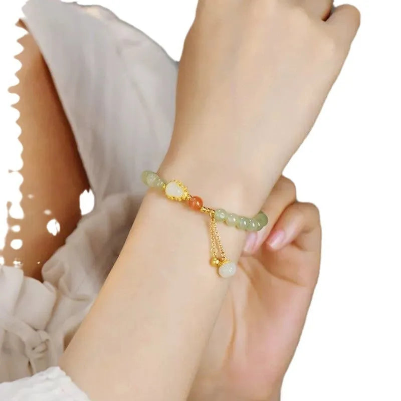 Hand-strung jade bracelet with a gold gourd charm and fu character charm.