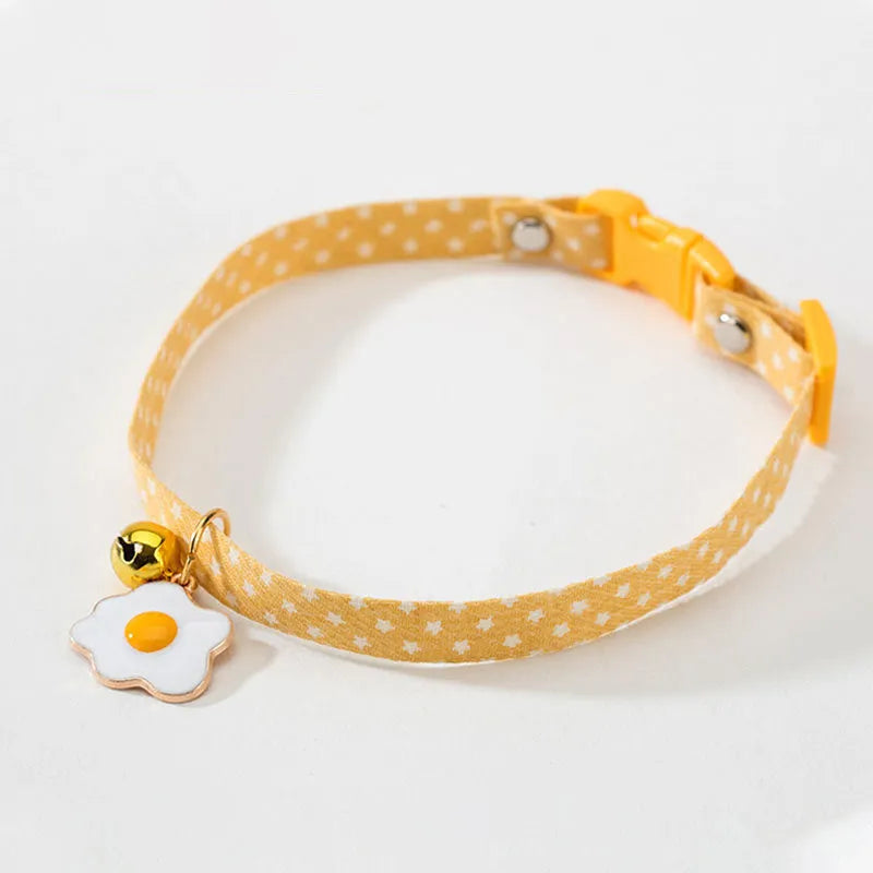 Green adjustable cat collar with bell pendant and bow tie on a small dog