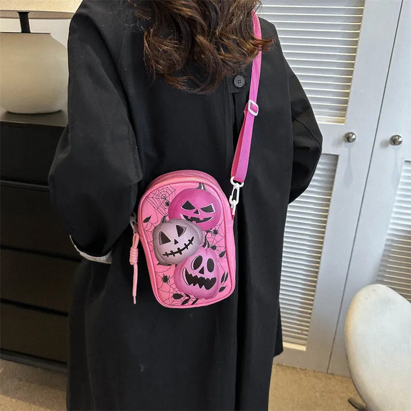 Black Halloween crossbody bag with graffiti print of cartoon pumpkins, ghosts, and bats.