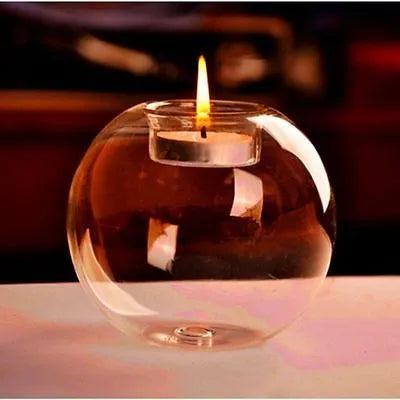 Handmade round hollow blown glass candle cup on a table.